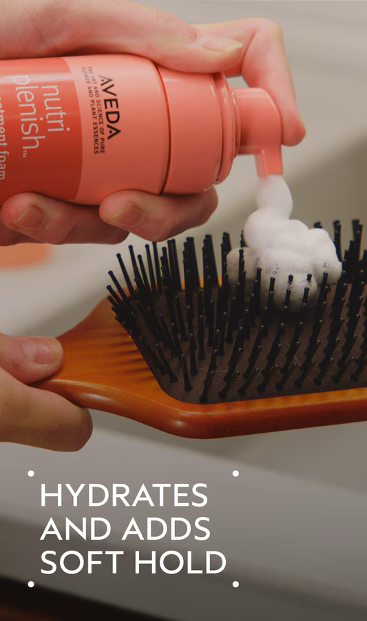 Aveda hair product being applied to a brush with text 'Hydrates and adds soft hold'. Aveda Nutriplenish Styling Treatment Foam 6.7oz can, lightweight foam that nourishes, defines, and enhances hair texture while providing soft, flexible hold.
