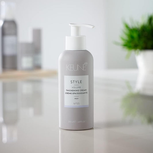 Keune Style Volume Thickening Cream bottle on a white surface with blurred background. Keune Style Volume Thickening Cream Prep 6.8oz tube, styling cream that adds body, thickness, and fullness while providing lightweight, manageable hold.