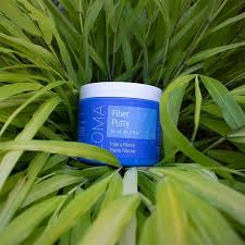 Blue jar with white lid on green grass. Loma Fiber Putty 3oz jar, styling putty that provides flexible hold, texture, and definition while adding volume and control without stiffness or residue