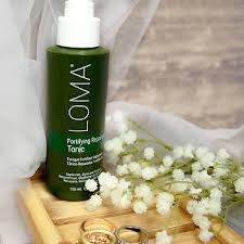 Loma bottle on a wooden tray with flowers and a wooden spoon