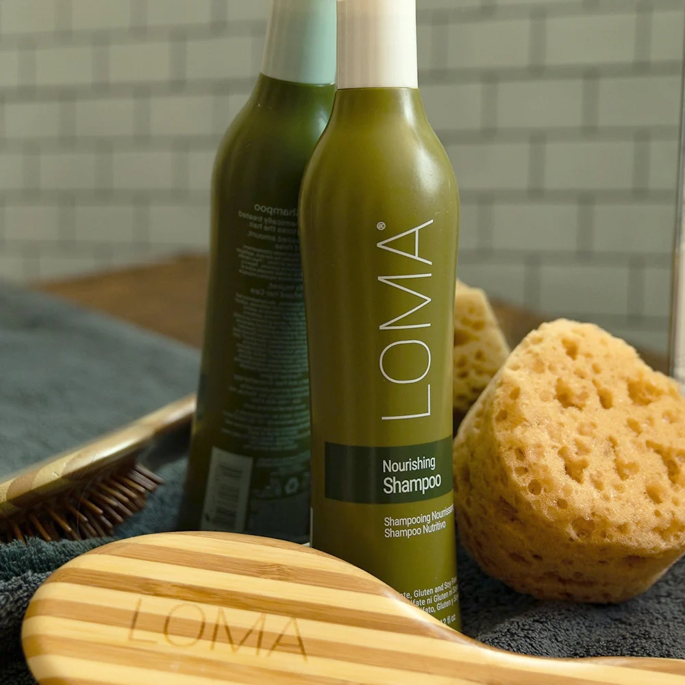 Loma shampoo bottle with a brush and sponge on a towel in a bathroom setting