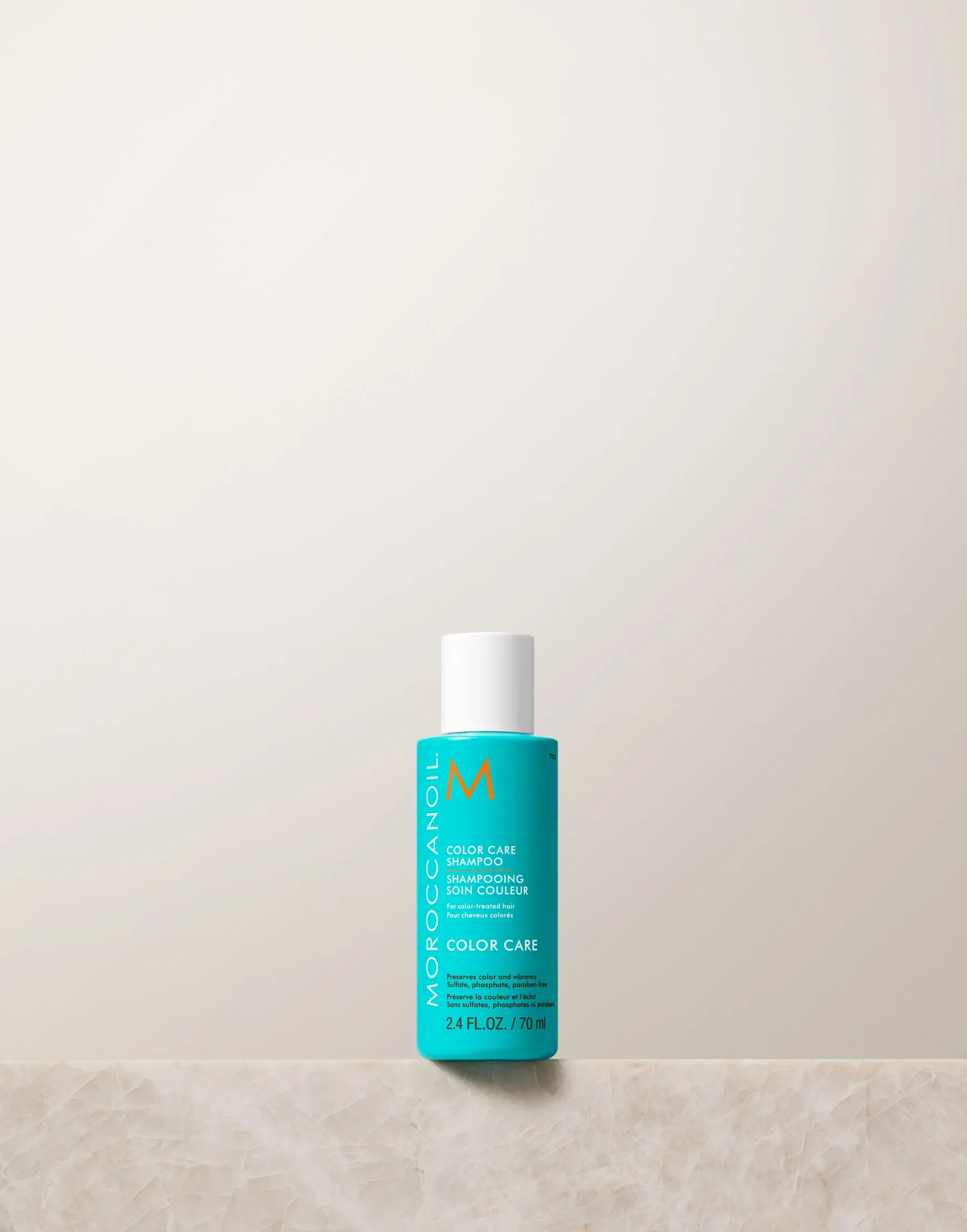 Blue bottle of Moroccanoil product on a beige surface