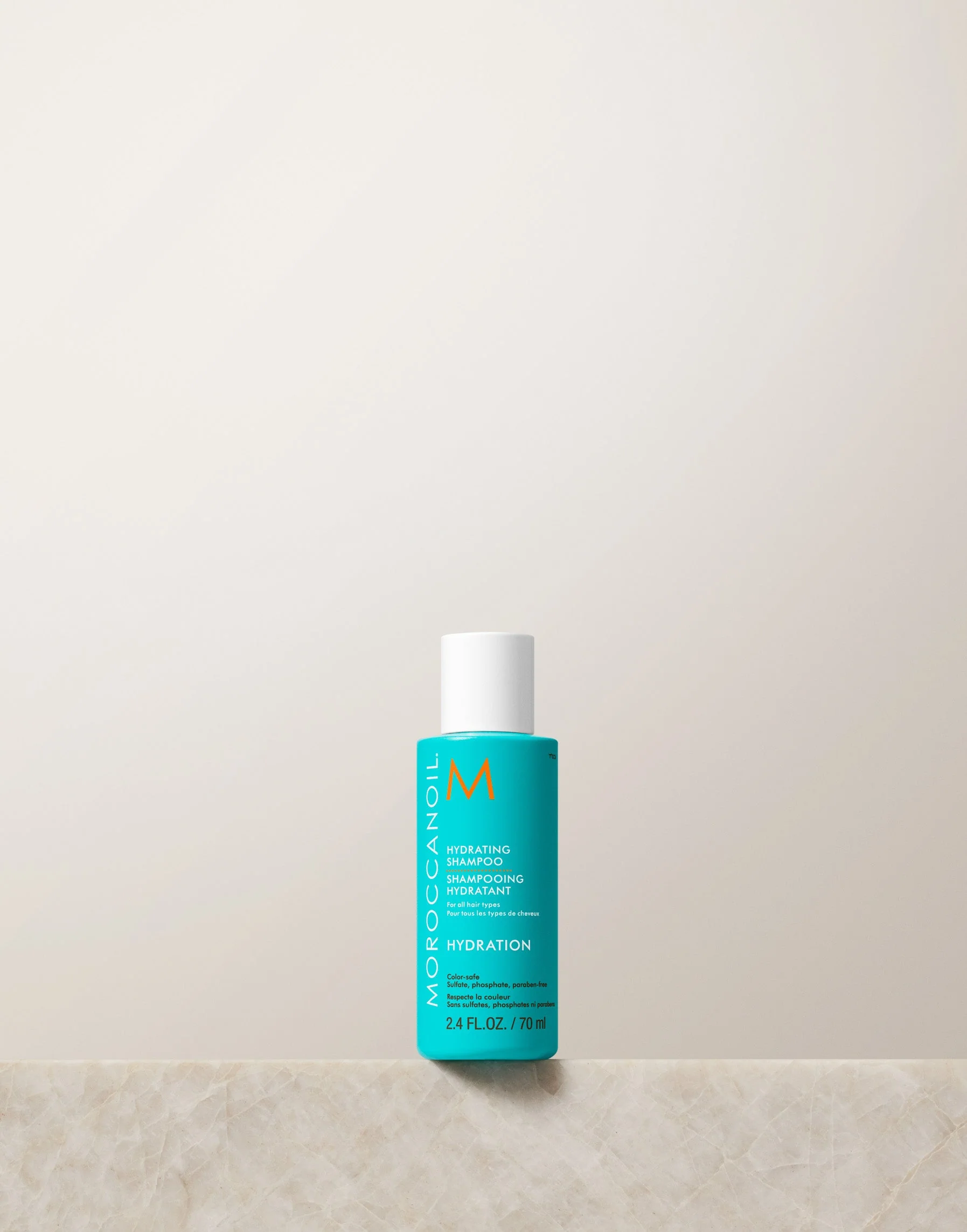 Blue bottle of Moroccanoil product on a light beige background
