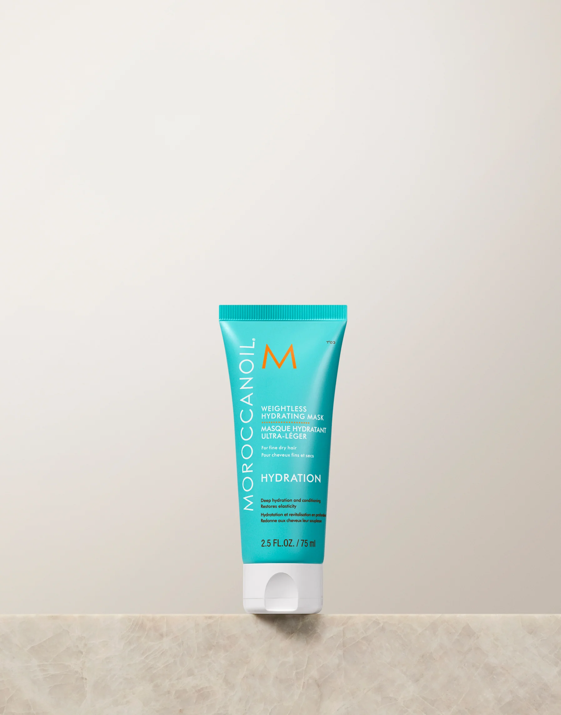 Moroccanoil tube on a beige surface with a light gray background